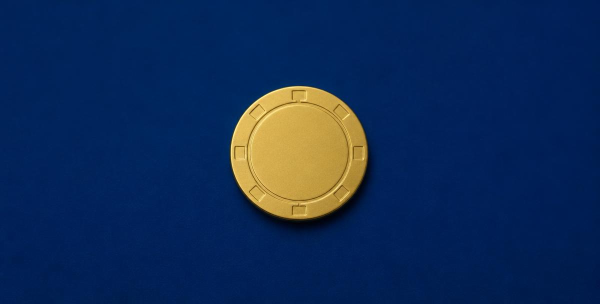 A single gold casino chip on a plain navy background